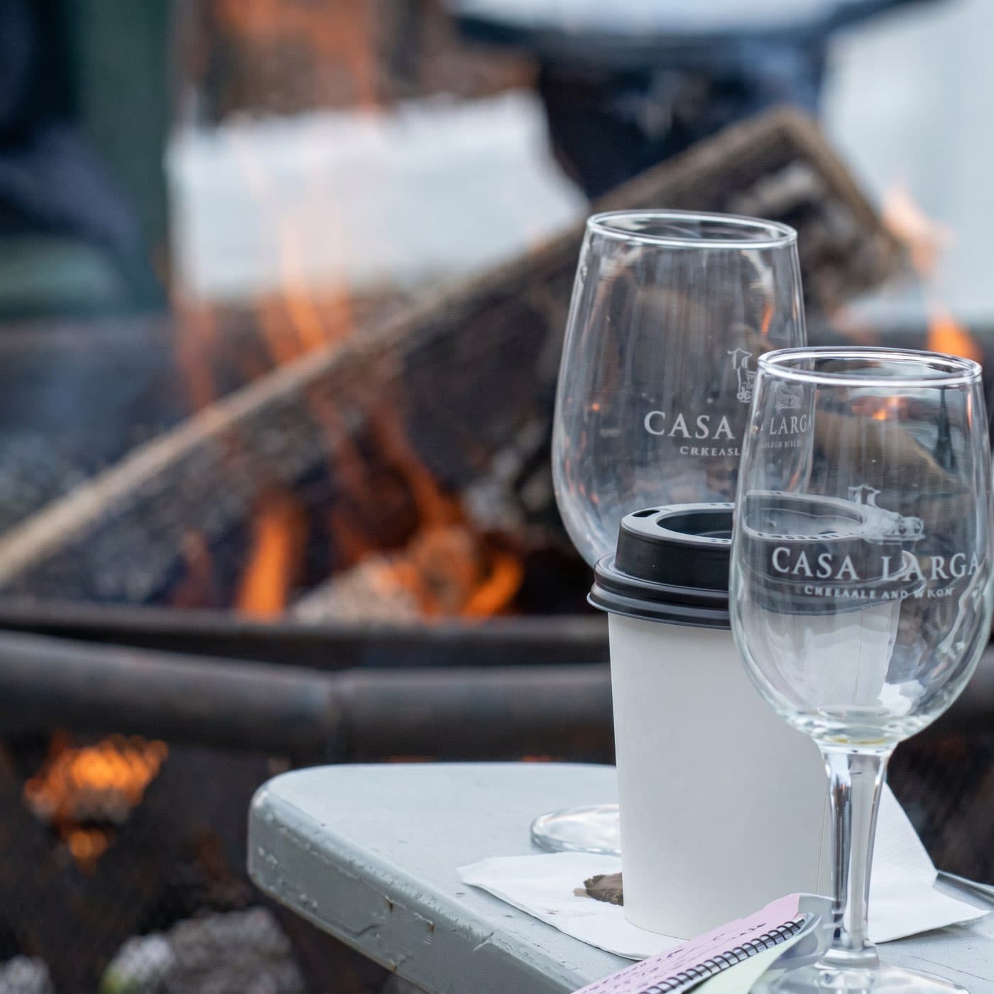 Casa Larga branded wine glasses beside an outdoor fire pit in winter