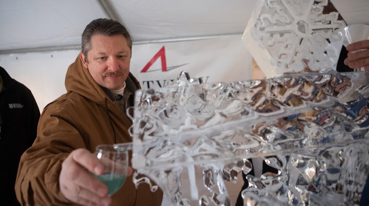 Guest pouring wine through a carved ice luge at the festival Ice Lounge