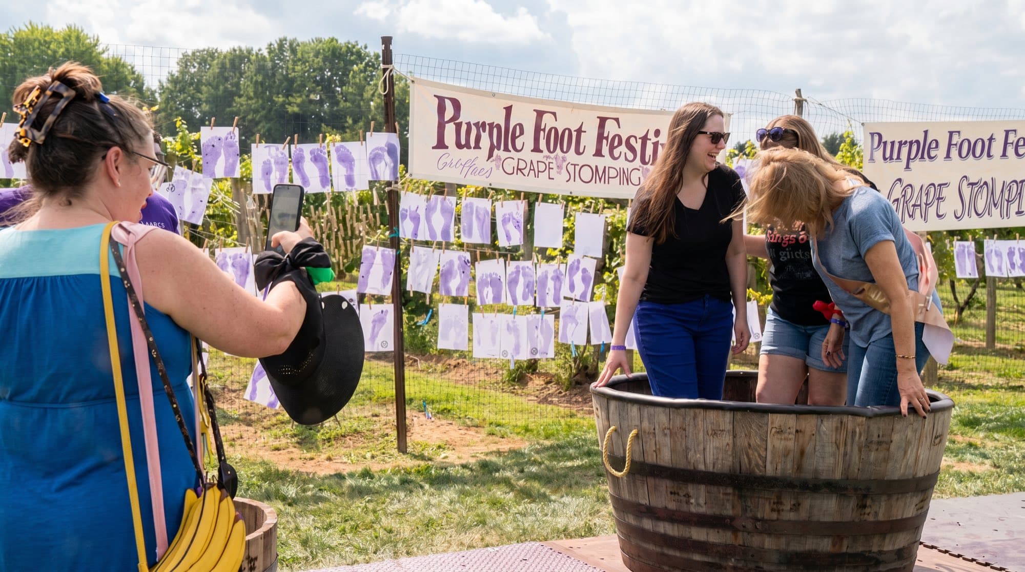 Guests stomping grapes in a barrel under the Purple Foot Festival grape-stomping banner